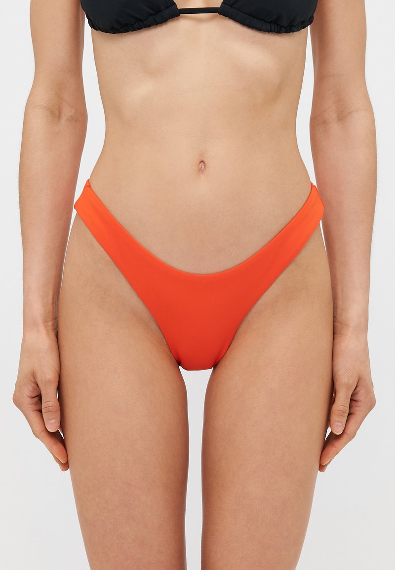 Oranžni bikini spodnji del z visokim izrezom, gladko teksturo in minimalno pokritostjo. Ima preprost dizajn brez okrasnih elementov.