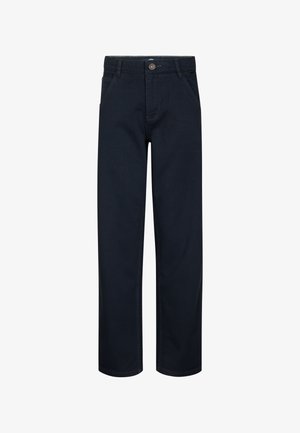 T-shirt di cotone azzurro chiaro con un piccolo logo nero sul petto, abbinata a pantaloni navy a gamba larga e sneakers bianche.