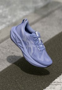 Light purple running shoe with mesh upper, padded collar, and textured sole, featuring subtle logo accents and lace closure.