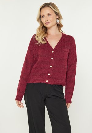 Burgundin neulecardigan, jossa on V-kaula-aukko, pitkät hihat ja kuusi kermaista nappia. Sisältää tekstuurin ja lyhyen istuvuuden.