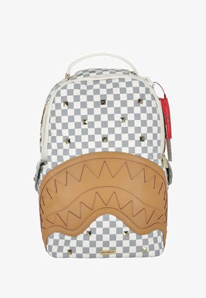 Zaino con motivo a scacchi grigio e bianco, fondo in pelle marrone con design a zigzag, borchie dorate e manico per il trasporto sulla parte superiore.