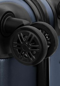 Ruote in plastica nera attaccate a un corpo della valigia blu con texture, dotato di una cerniera e materiali resistenti per la comodità durante i viaggi.