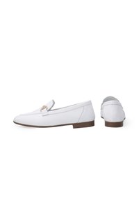 Weiße Lederloafers mit einem schlanken, flachen Design. Sie verfügen über einen kleinen Vordersteg mit metallic Details und einer braunen Gummisohle.