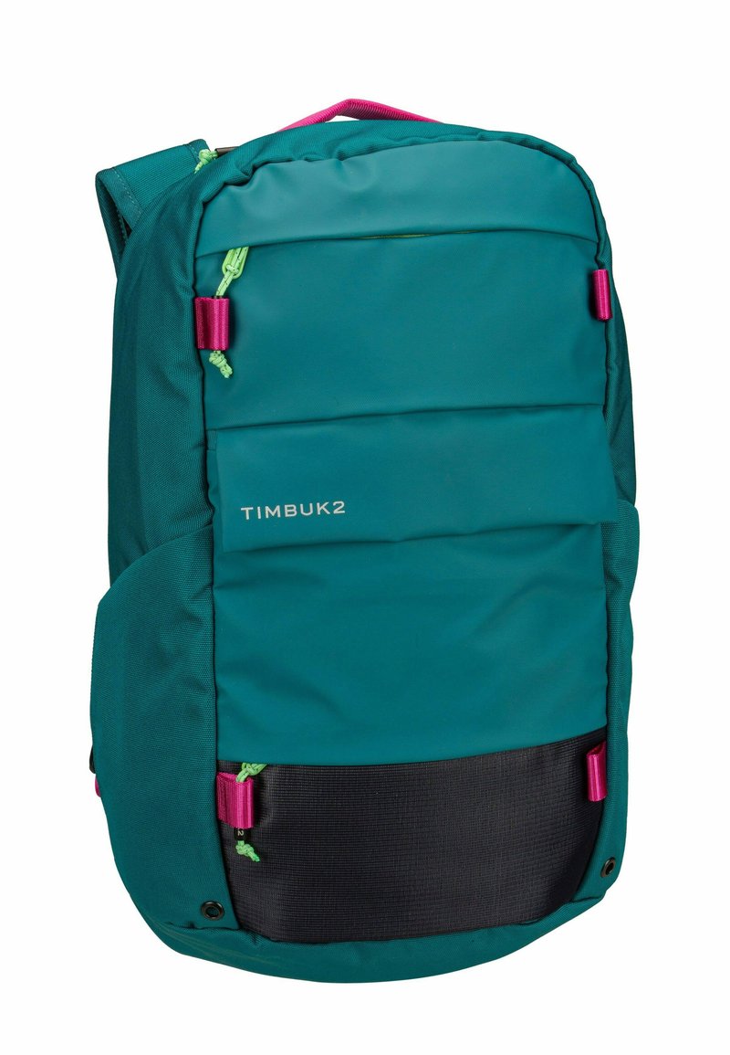 Teal backpack with padded front, purple accents, adjustable straps, and a textured black bottom panel. Features branding on the side.