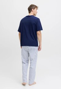 Tumši zils kokvilnas T-krekls, saskaņots ar baltām un zilām rūtainām pidžamas biksēm. Īsām piedurknēm, ērtā piegriezumā un mīkstā auduma tekstūrā.