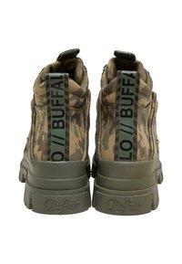Paire de baskets montantes camouflage vert avec semelles épaisses et marquage noir "BUFFALO" sur les languettes arrière et les semelles.