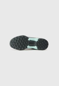 Schwarze Gummisohle mit strukturiertem Muster und einem hellblauen Akzent. Enthält dreieckige und hexagonale Profilierungen für besseren Grip.