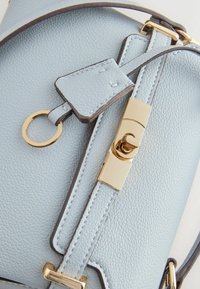 Világoskék, texturált bőr táska aranyszínű csavarozható zárral, kulcstartóval és pánt részlettel.