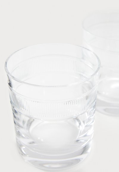 Vasos de cristal transparente con textura acanalada cerca de la parte superior y sección inferior lisa, con base gruesa. Se ven dos vasos.