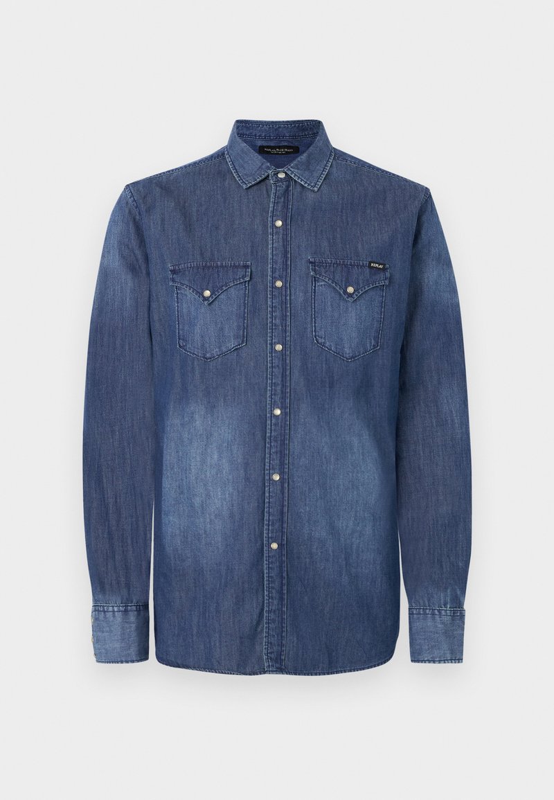 Camisa de denim en un degradado de azul con cierre de botones en la parte delantera, mangas largas, dos bolsillos en el pecho y cuello con puntas. Presenta botones en tono plateado.