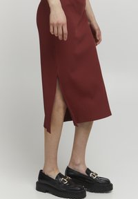 Ribbes burgunderfarbenes Midikleid mit einem seitlichen Schlitz. Kombiniert mit schwarzen Slippern mit einer goldenen Schnalle und dicker Sohle.