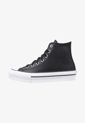 Adidași înalți negri din pânză, cu vârf din cauciuc, talpă albă cu dungi negre și șase gauri metalice pentru șireturi.