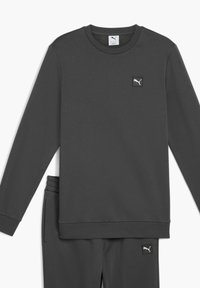 Dunkelgrauer Pullover mit langen Ärmeln, rundem Halsausschnitt und einem kleinen schwarzen quadratischen Logo. Weicher, strukturiertes Material mit teilweise sichtbaren passenden Hosen.