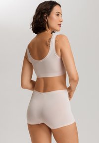 Ljusrosa sömlös bh och shorts-set, gjort av stretchigt tyg. Enkelt mönster med breda remmar och en slät textur.