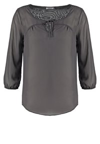 Grå genomskinlig blus med långa, mjukt smyckade ärmar, rund halsringning och en knytdetalj fram. Slätt tyg med en flödande design.