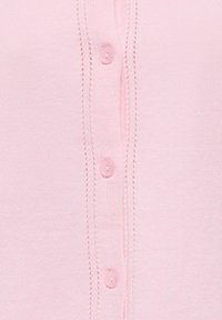 Tissu tricoté rose clair avec une rangée verticale de quatre petits boutons roses et des boutonnières assorties.
