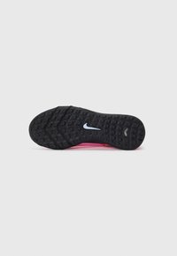 Svart gummisåle med teksturert grep, med en rosa overdel og reflekterende Nike-svush på utsiden.