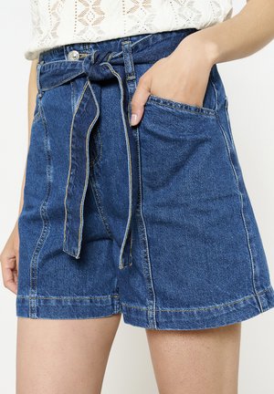 Shorts de mezclilla en un lavado azul medio con un cinturón atado, bolsillos frontales y costuras de contraste a lo largo de las costuras.
