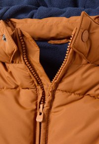 Orange padded jacket with a zippered closure, featuring a navy fleece lining. The collar has snap buttons and visible stitching detail.