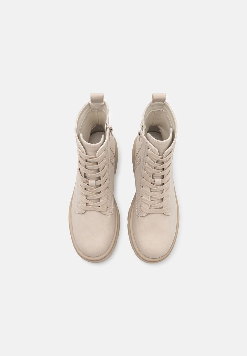 Une paire de bottines en cuir beige à lacets avec des fermetures éclaires latérales, bouts ronds et tirettes, vues de dessus sur un fond blanc uni.