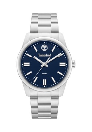 Srebrna kovinska zapestna ura z modrim številčnico, srebrnimi označevalci ur, logotipom Timberland in tremi kazalci, ki kažejo čas 10:09:38.