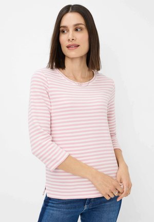 Maglietta a maniche lunghe a righe rosa chiaro e bianco con scollatura rotonda e spacchi laterali, realizzata in un tessuto testurizzato. Indossata con jeans blu.