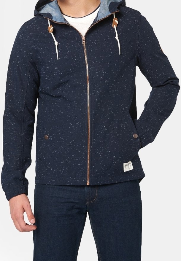 Mörkblå zip-jacka med fläckigt mönster, snörning i huvan och beige detaljer. Har två sidofickor och en liten etikett på fållen.