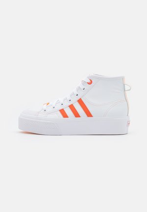 Hvid høj-top sneaker med orange striber, hvide snørebånd, tyk sål og lille hælkrog vist fra siden på en ensfarvet baggrund.