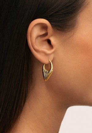 Goldfarbene Creolen mit einem strukturierten, geschichteten Design in Fächerform, die an einem Ohr mit dunklem Haar vor einem neutralen Hintergrund präsentiert werden.