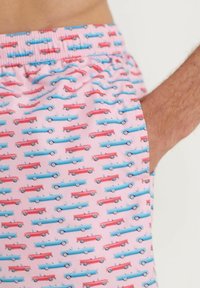 Rosa Badehose mit einem sich wiederholenden Muster aus blauen und roten Autos. Elastischer Bund mit einer Seitentasche, aus leichtem Material gefertigt.