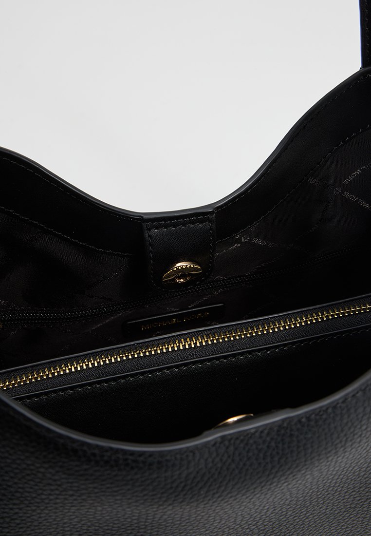 Zwarte leren handtas met een gestructureerde buitenkant, gouden rits en een gladde binnenvoering. Beschikt over een magnetische sluiting en een merklabel aan de binnenkant.