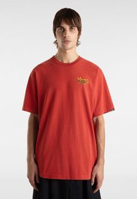 Rød bomulds t-shirt med en afslappet pasform, der har gult "Vans" logo broderi på brystet og korte ærmer. Enkel design, ingen mønstre.