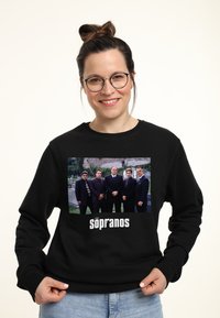Felpa nera con una stampa grafica frontale di sei personaggi all'aperto, con il testo "The Sopranos" in un audace font bianco.