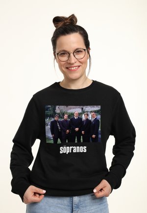 Czarny sweatshirt z grafiką na przodzie przedstawiającą sześciu bohaterów na świeżym powietrzu, z napisem "The Sopranos" w pogrubionej białej czcionce.