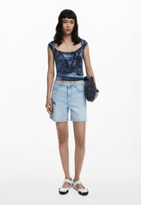 Blue, fitted top with a subtle pattern, paired with light blue denim shorts featuring floral embroidery, and white shoes with black soles.