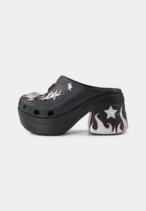 Tamanco preto com salto elevado, apresentando detalhes metálicos prateados, padrões de chamas em vermelho e branco, e decorações de estrelas. Exterior texturizado.