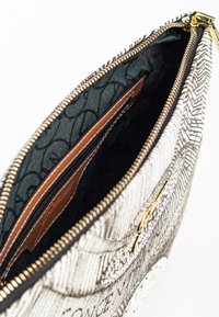 Borsa con zip, caratterizzata da un esterno a motivi bianchi e neri testurizzati, con una fodera verde scuro e vani per carte in pelle marrone all'interno.