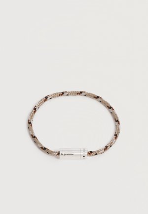 Bracelet en cordon tressé beige et marron avec un fermoir en argent gravé de « le gramme » et des marques « 925 ».