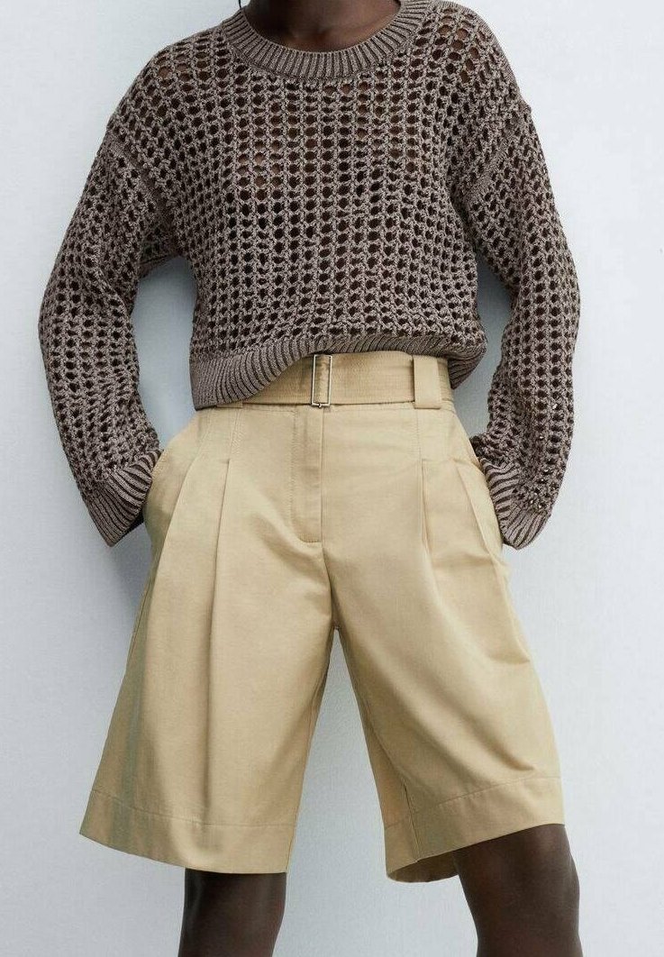 Pull en tricot marron avec une texture en maille ajourée, associé à un short plissé beige clair avec poches latérales et taille haute.