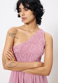 Robe rayée rouge et blanche avec un design à une épaule. Présente une texture plissée et une taille cintrée. Tissu lisse avec une jupe fluide.
