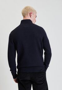 Maglione lavorato a maglia blu navy con colletto alto, polsini e orlo a coste. Presenta una vestibilità standard e un design semplice senza motivi visibili.