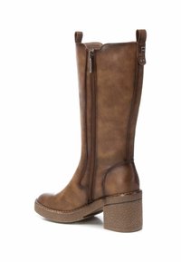 Bota alta de imitación cuero marrón con cremallera lateral, punta redondeada y tacón cuadrado texturizado. Incluye un lazo en la parte superior para facilitar su uso.