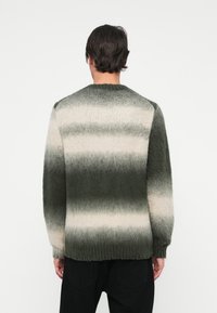 Maglione lavorato a maglia con un motivo gradiente in tonalità di verde e crema, caratterizzato da un colletto rotondo e polsini e orlo a coste. Finitura morbida e texture.