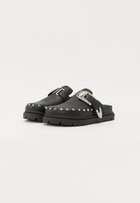 Black leather clogs with silver studs along the front edge, thick black sole, and a buckle accent on the strap. Smooth, matte finish.