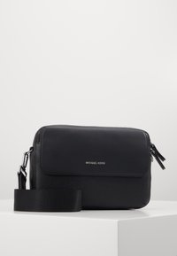 Borsa a spalla in pelle nera con finitura testurizzata, patta liscia, logo in argento e tracolla regolabile. Caratterizzata da chiusura con zip e design elegante.