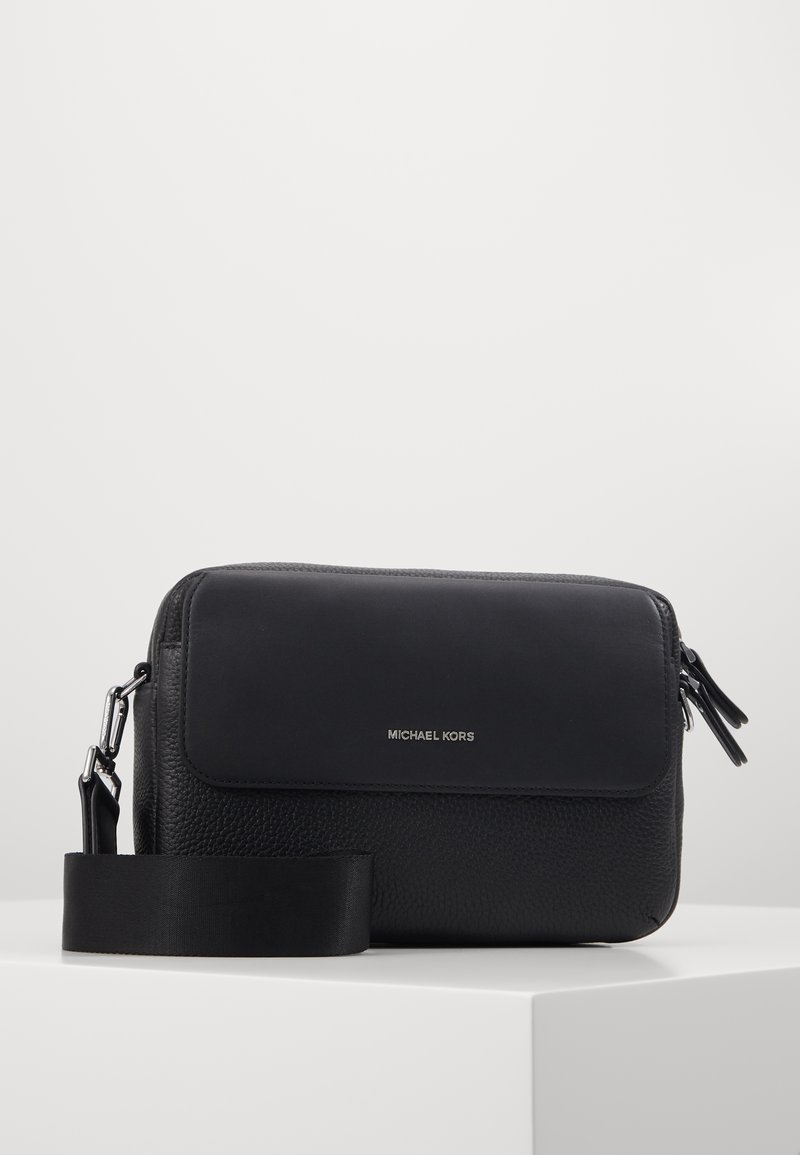 Borsa a spalla in pelle nera con finitura testurizzata, patta liscia, logo in argento e tracolla regolabile. Caratterizzata da chiusura con zip e design elegante.