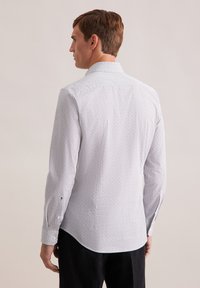 Witte lange mouw shirt met een klein zwart patroon, knoopmanchetten en een klassieke kraag; gladde stof en een gebogen onderrand.