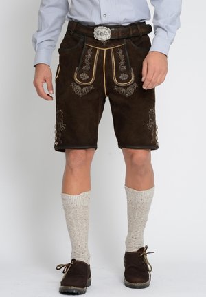 Braune Lederhosen mit aufwändiger goldener Stickerei und floralen Mustern, kombiniert mit knielangen strukturierten weißen Socken und dunklen Schuhen.
