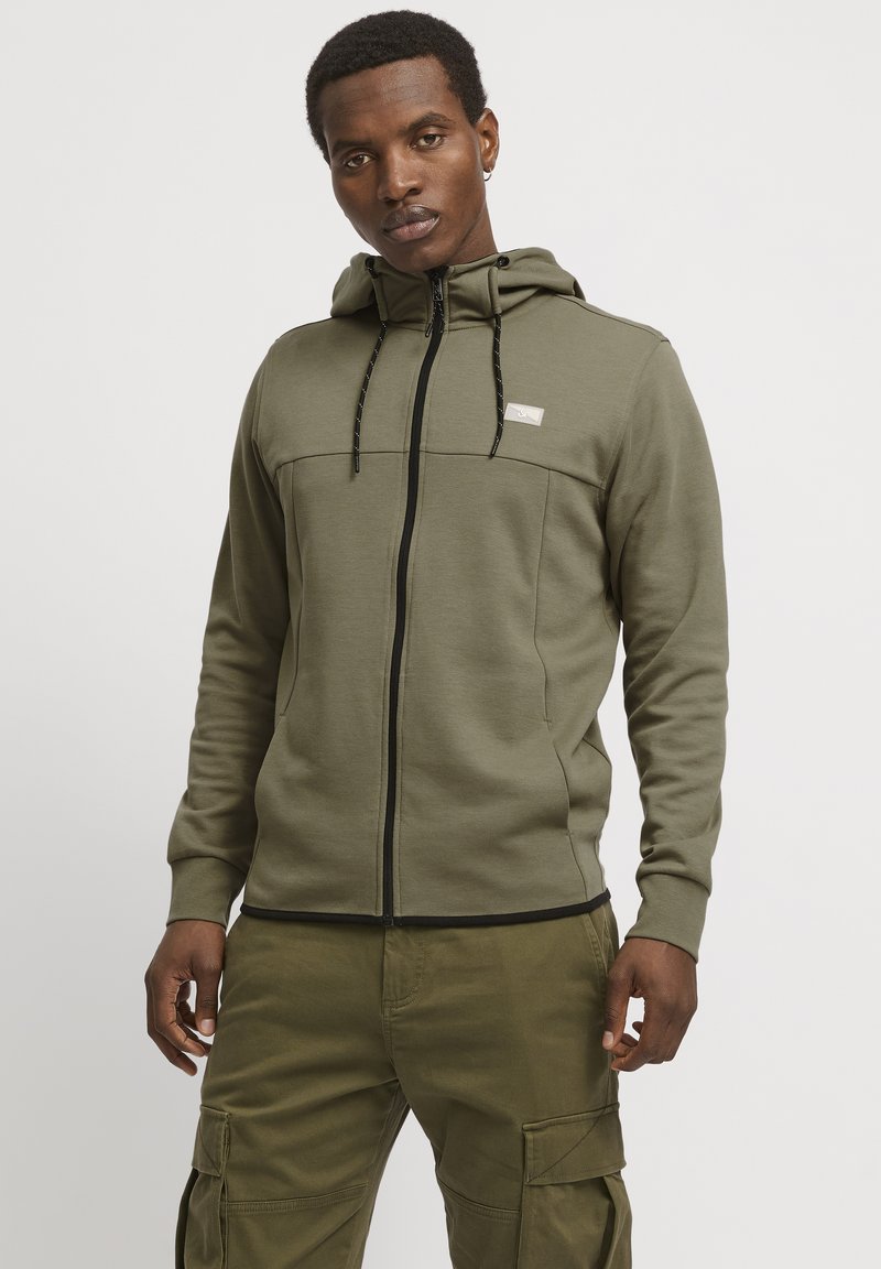 Olive green zip-up hoodie with a textured finish, featuring a subtle logo, contrast black zipper, and adjustable drawstring hood.
