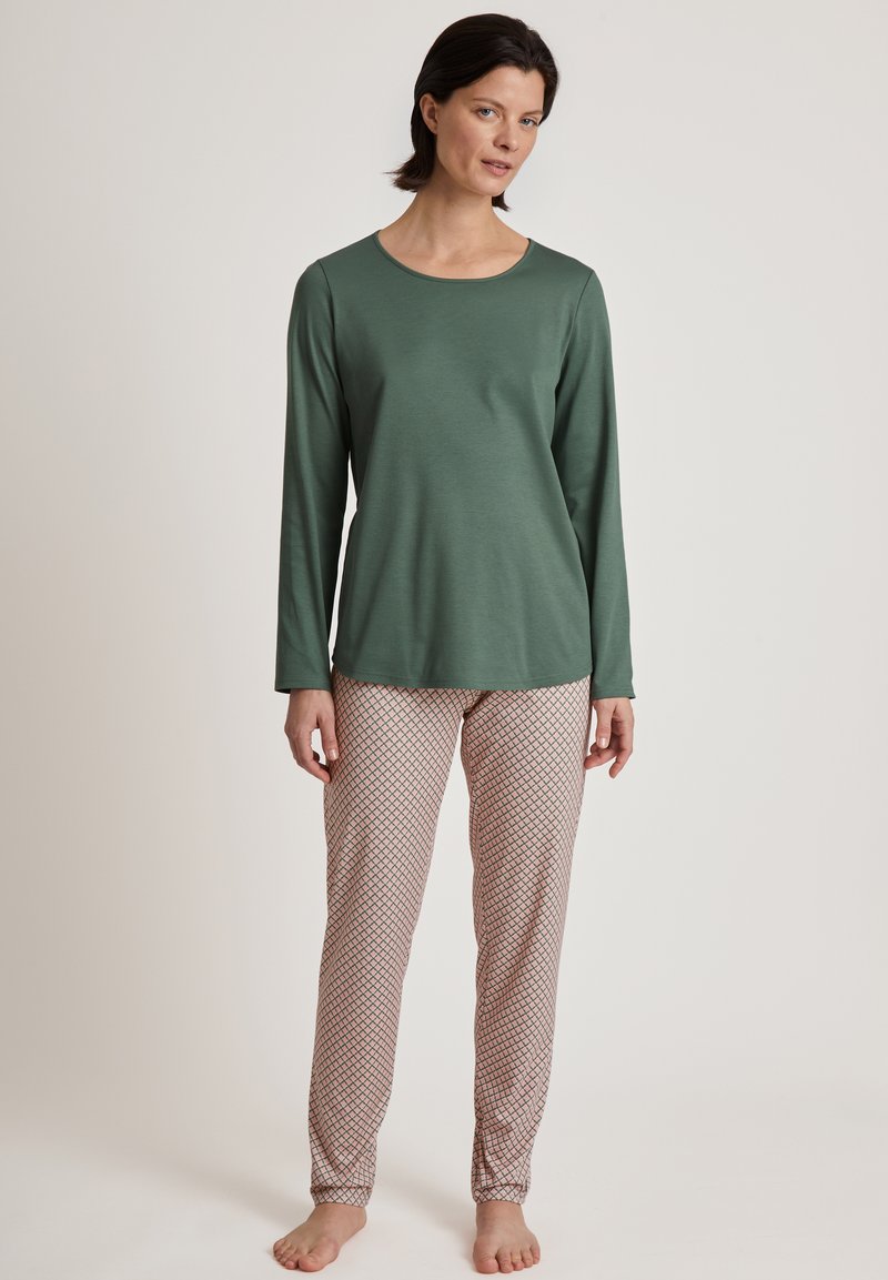 Maglietta verde a maniche lunghe abbinata a pantaloni da pigiama leggeri e patterned in rosa chiaro con un design a diamante. Tessuto morbido con una vestibilità rilassata.